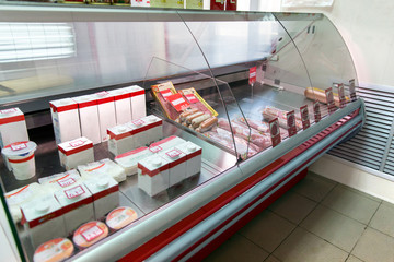 Counter with milk and sausage in store. Refrigerator shelves with different products