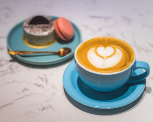 Cappuccino in blue cup with dessert on the table