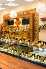 Baked baguettes and pies on showcase in bakery shop. Inscriptions in russian with the name baking: cheesecake, bun, pie, baguette and others. 30 percent discount offer