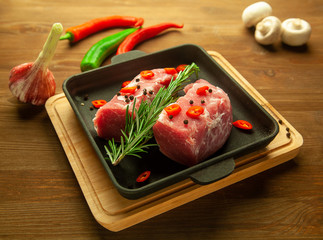 Raw tenderloin  on cooking pan with rosemary, garlic, chili peppers