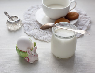Healthy breakfast egg and yoghurt jug served on white dresser scarf with silver spoon. 