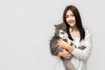 Asian woman with long hair wearing a white shirt is carrying a grey Persia Cat.