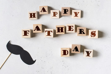 Fototapeta na wymiar Fathers day greeting card flat lay with mustache and type on wooden toys block