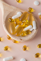 Natural vitamins and supplements on wooden spoons on pink background. top view flat lay close up...