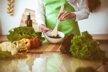 Unknown human hands cooking in kitchen. Woman is busy with vegetable salad. Healthy meal, and vegetarian food concept