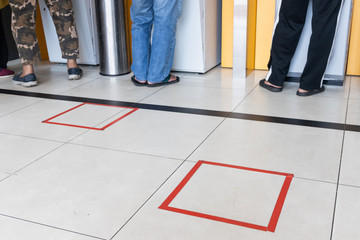 People practicing social distancing in queue towards auto teller machine in bank