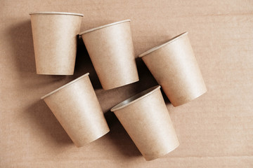 Disposable paper cups on kraft paper background. Eco friendly disposable tableware. Zero waste concept. Top view. Copy, empty space for text