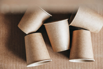 Disposable paper cups on kraft paper background. Eco friendly disposable tableware. Zero waste concept. Top view. Copy, empty space for text