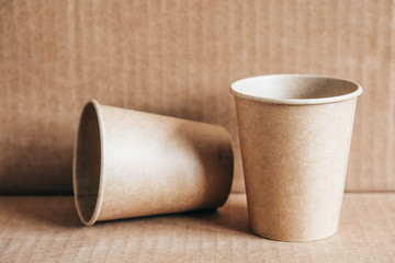 Disposable paper cups on kraft paper background. Eco friendly disposable tableware. Zero waste concept. Copy, empty space for text