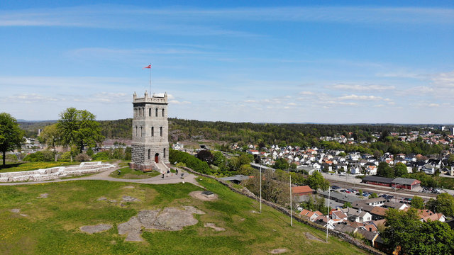 Created by dji drone camera of Slottsfjell an architecture building from medieval times in the oldest city of Norway with a village in the background and the Norwegian flag on top in the summer
