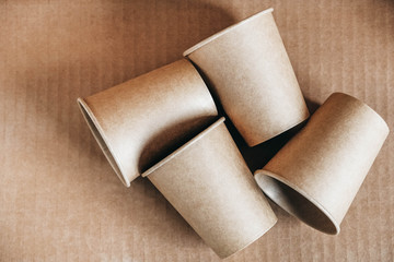 Disposable paper cups on kraft paper background. Eco friendly disposable tableware. Zero waste concept. Top view. Copy, empty space for text