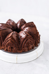 Homemade Chocolate bundt cake with melted chocolate on white background.Close up view, selective focus