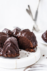 Homemade Chocolate bundt cake with melted chocolate on white background.Close up view, selective focus