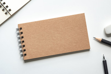 Close up. Kraft Paper Cover Spiral Notebook with Pencil, Eraser and Open Notebook on white...