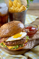 cheeseburger with egg and bacon, a glass of cola and fries