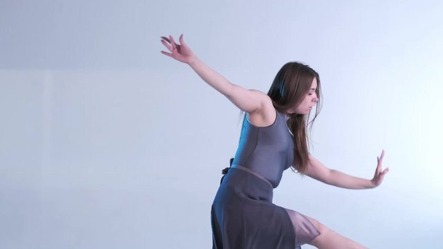 Medium long shot of young beautiful woman dancer in a dress with long hair emotionally dancing contemporary, modern ballet dance, slow motion, isolated