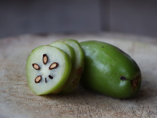 whole Madan fruit and dissecting Madan fruit and Leaves on the wood floor.Garcinia schomburgkiana.