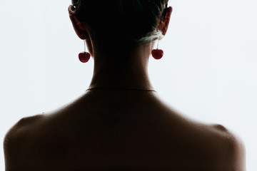 silhouette of a girl on a white background with red cherry shaped earrings