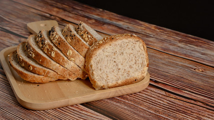 Slice whole grain bread on the wooden table.