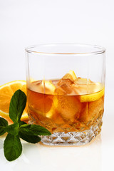 Glass of whiskey with ice and lemon, white background, close-up