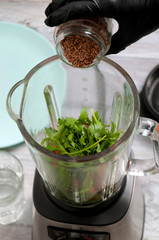 Blender, carrot, parsley, dill on a gray wooden table. Girl makes a smoothie of vegetables. Healthy lifestyle. Dietary nutrition. Carrots and greens close-up.