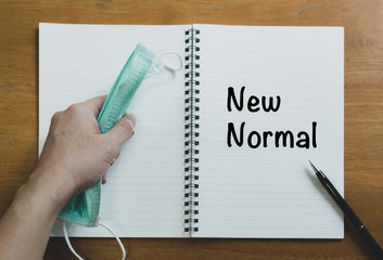 picture of hand using pen writing phase on the diary book with surgical face mask on top on the...