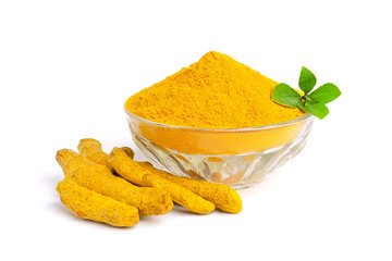 Turmeric powder in glass bowl with green leaves and dry roots isolated on white background.