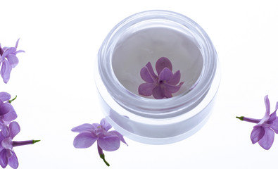 face cream with pink petals on light background