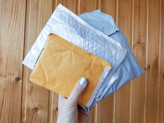 Three postal parcels small package white, gray and yellow on wooden background surface