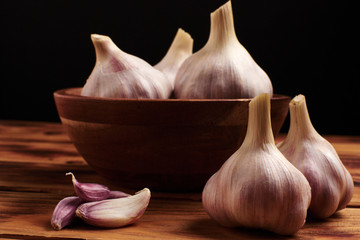 Fresh young garlic in a wooden cup on a wooden table.