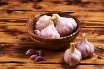Fresh young garlic in a wooden cup on a wooden table.