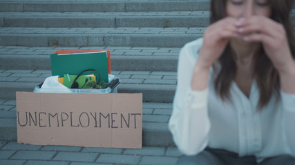 Crisis 2020 banner. People lost their work. Unhappy brunette young business woman feel worried about job loss sitting on stairway. Pandemic. Quarantine.