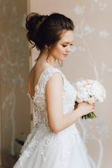Portrait of a bride. A young girl in a beautiful wedding dress with a bouquet of flowers. Close-up, makeup, hairstyle.