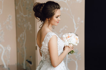 Portrait of a bride. A young girl in a beautiful wedding dress with a bouquet of flowers. Close-up, makeup, hairstyle.