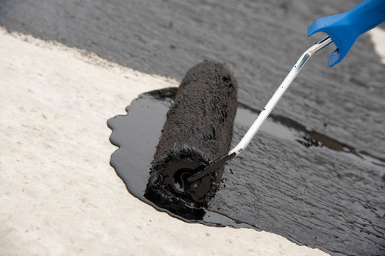 Worker applies bitumen mastic on the foundation