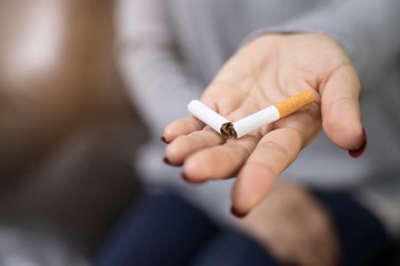 Close-up of a person holding a cigarette in their hand.