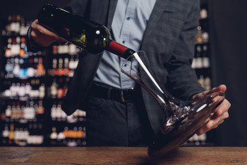 Sommelier pouring red wine into carafe decanter to make aeration drink