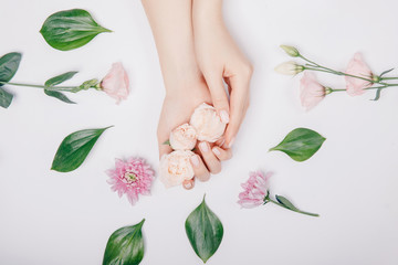 Obraz na płótnie Canvas Close-up beautiful sophisticated female hands with pink flowers on white background. Concept hand care, anti-wrinkles, anti-aging cream, spa