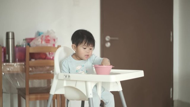 Cute Malaysian baby girl yawning after eating and standing up from chair