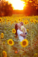 Portrait of a happy family, mom with her son on summer nature in a field of sunflowers