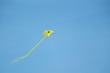 Small Yellow kite flying in the blue sky