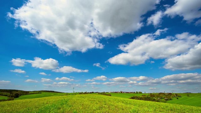 time lapse clouds on blue sky in green field landscape at sunny day