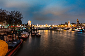 Naklejka premium beautiful urban landscape of the seine river bordered the city of paris, in the river you can see some boats that make a house, a bridge in the distance and a sky with blue color and clouds