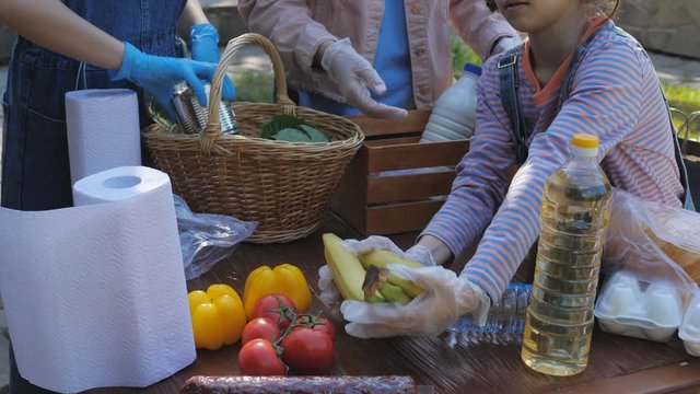 Close-up of volunteers putting essential food in a basket to help the poor.