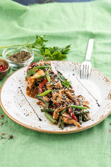 Plate of asian chicken salad with bean, pepper and sesame seeds on green background