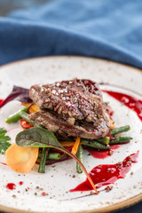 sirloin steak with green beans on white plate on blue background