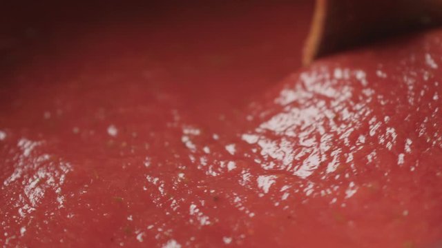 Slow motion stir tomato puree with spoon macro shot