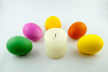 Some easter eggs, with a white easter-candle, isolated on white background, colored by easter bunny
