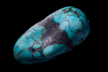 Raw turquoise gemstone rock isolated on a black background.