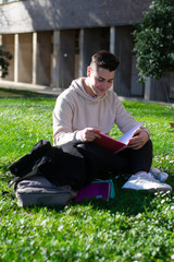 Obraz premium Teenager sitting on the school grass while reading a book